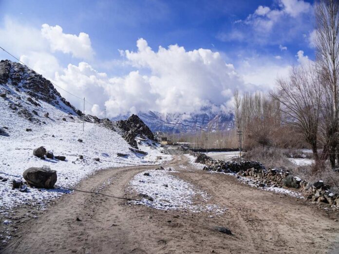 Caption: Leh: A view of a snow-covered road and surrounding mountains after fresh snowfall in Leh on Tuesday, March 24, 2026. (Photo: IANS)