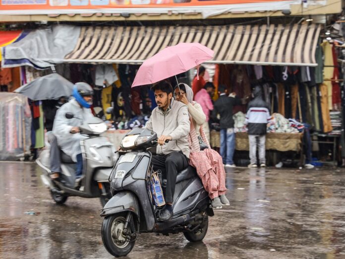 Jalandhar: People ride scooters with umbrellas amid continuous rainfall affecting daily life in Jalandhar on Thursday, March 19, 2026. (Photo: IANS)