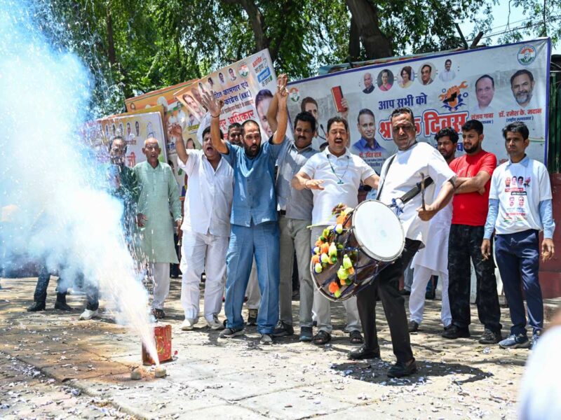 CONGRESS - bolebharat Group of men cheering as a man with a decorated drum leads a celebration; sparks burst from a ground firework nearby.