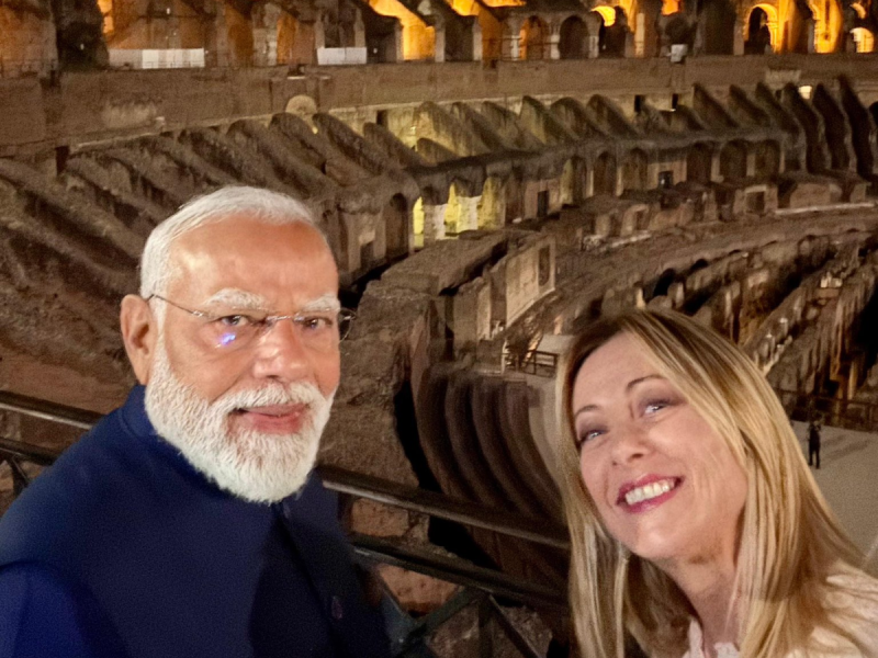 Smiling couple taking a selfie inside a dimly lit ancient amphitheatre, with stone arena walls in the background.
