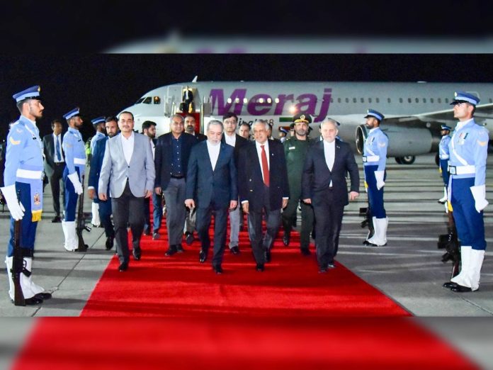 Dignitaries in suits walk down a red carpet at night after arriving by jet, flanked by uniformed guards on the tarmac.