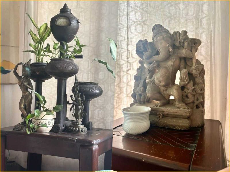 naresh saxena house - bolebharat Decorative split scene: left a black metal plant stand with plants and small statues on a dark wooden table; right a carved stone Ganesha statue on a wooden table with a white ceramic cup nearby.