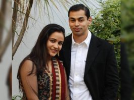 Smiling couple posing outdoors with greenery in the background.