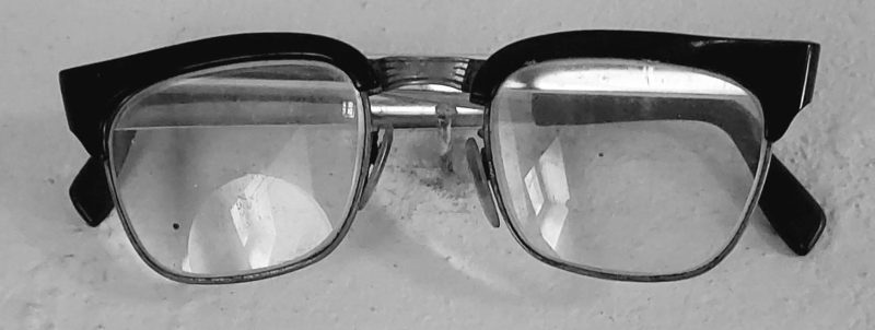 Black-framed eyeglasses with clear lenses resting on a light surface.