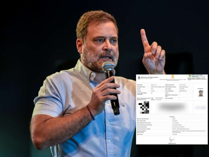 Man with short hair and beard speaks into a handheld microphone on stage, raising his index finger as if making a point.