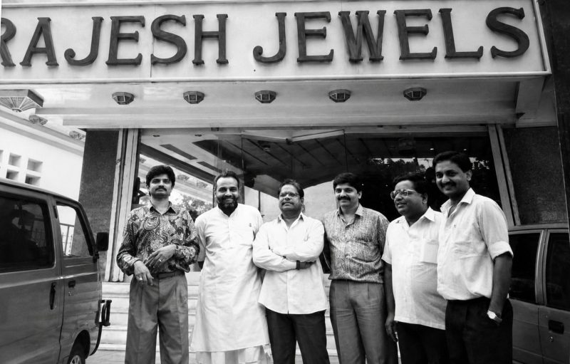 Six men pose in front of the Rajesh Jewels storefront.