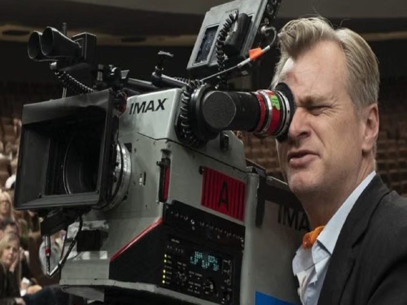 Cameraman operating an IMAX motion-picture camera on a crowded set with spectators in the background.