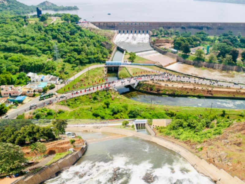 KAVERI RIVER METTUR DAM - bolebharat Aerial view of a dam with a spillway, adjacent road lined with trees, and a lush green landscape nearby