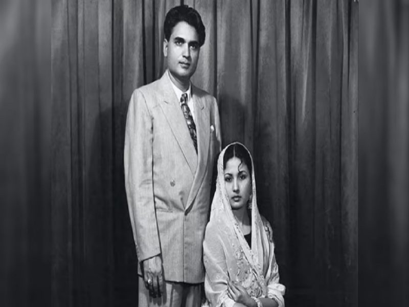 A formal black-and-white portrait of a man in a suit standing beside a seated woman in a traditional veil and dress.