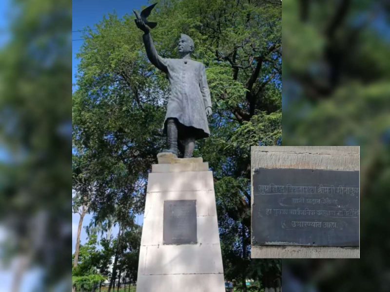 Statue of a man in a long coat on a tall pedestal in a park, raising his right arm as a bird flies away. (Inset shows a plaque with inscription)
