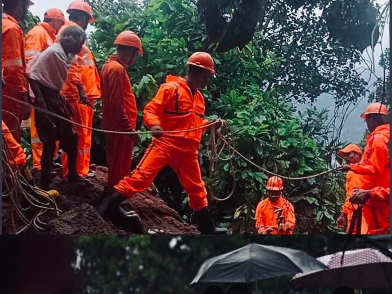 Group of workers in bright orange uniforms and helmets using ropes on a muddy hillside during a rescue operation.